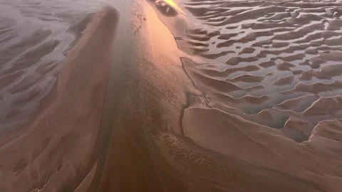 Sunset on tidal sand patterns with pool reflections. Flight forwards. Stock Footage 287553974