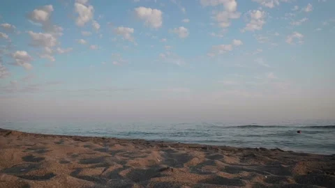 Sunset time on beach. Nice clouds and empty beach. A single woman is swimming fa Stock-Footage 137694590