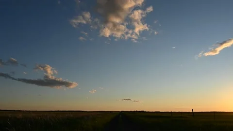 Sunset time lapse looking down a dirt road through rough farmland Stock Footage 220082641