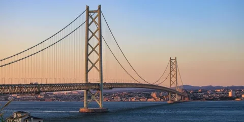 Sunset time lapse as tide and cargo ship convoy move under iconic Akashi Stock Footage 196494714