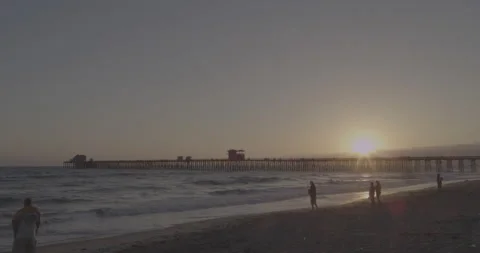 Sunset timelapse at a beach near a long pier, people silhouettes walking by Stock Footage 150436080