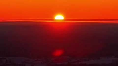 Sunset timelapse glowing with large sun above clouds at horizon creating 動画素材 331337814