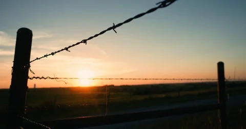 Sunset timelapse looking through Barbwire Fence Stock Footage 91565583
