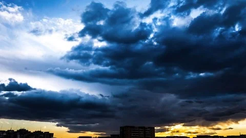 Sunset timelapse with stormy clouds moving above the crowded city buildings Stock Footage 75577345
