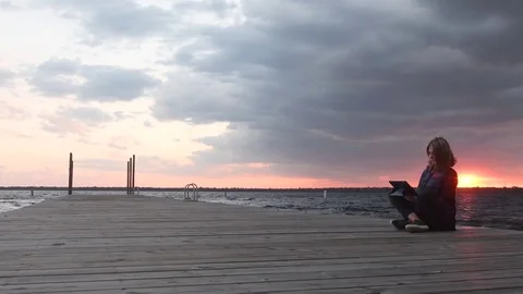 Sunset tracking shot of lady lakeside working on her tablet Stock Footage 71145915