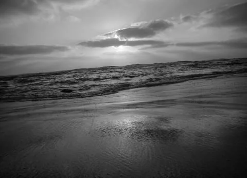 Sunset under a cloudy sky on a sandy beach in black and white 写真素材