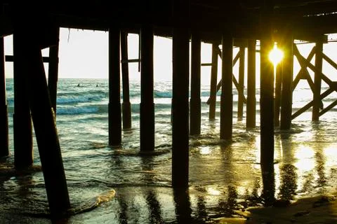 Sunset from under a pier with a surfer Stock Photos