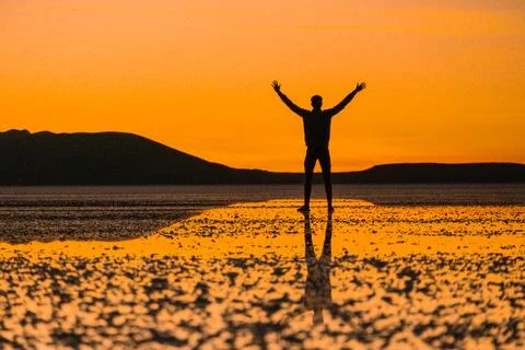Sunset at Uyuni salt flats with reflection of happy person Stock Photos