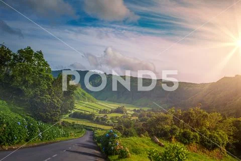 Sunset valley, drive road amoing mountains and green hills with lush and flow Stock Photos