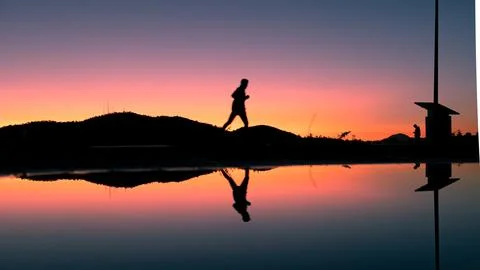 Sunset Vibe: Reflection of a Man Running by a Puddle Foto stock
