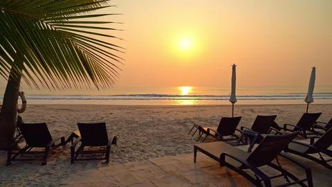 Sunset view on a beach with chairs and umbrellas Stock Photos