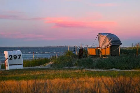 Sunset view of beach chairs and numbered beach boxes near ocean shore Stock Photos