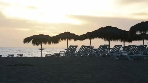 Sunset view on beach with sun beds and straw umbrellas Stock Footage 169866138