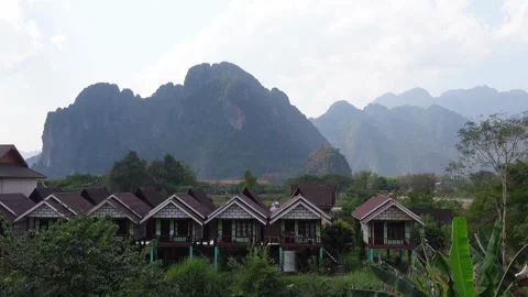 Sunset view of bungalows and beautiful Karst rock formations in Vang Vieng Stock Footage 293219726