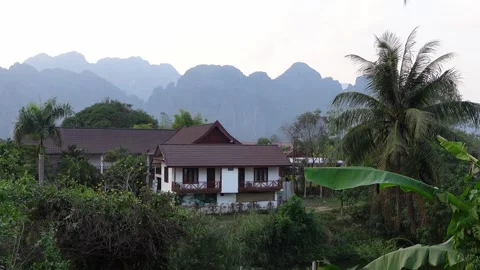 Sunset view of bungalows and beautiful Karst rock formations in Vang Vieng Stock Footage 293219792