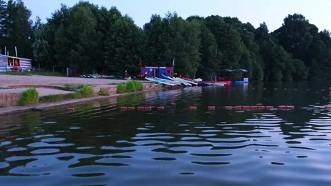 Sunset view of a calm lake with a shore facility storing paddleboards and kayaks Stock Footage 340356607