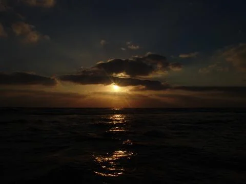 Sunset view on a calm sandy beach with cloudy sky and golden light. Stock-Fotos