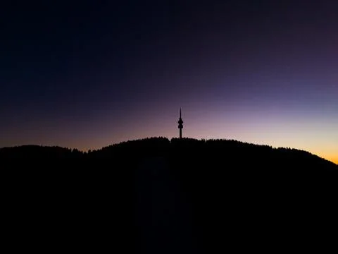 Sunset view of a communications tower on a mountain peak surrounded by tree.. Stock Photos