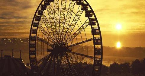 Sunset view of a ferris wheel against a golden sky near water Stock Illustration
