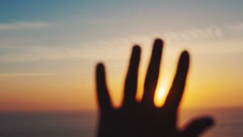 Sunset view with hand reaching out over the ocean at a beach location during Stock Footage 338244236