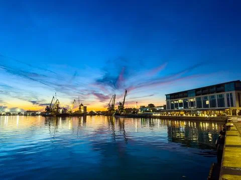 Sunset view of a harbor with cranes and buildings reflecting on the water d.. 库存照片