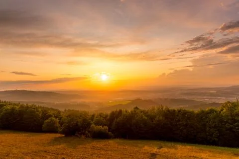 Sunset with view on landscape with fully colored clouds orange and purple and Фото