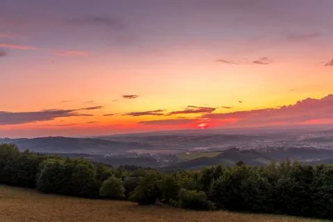 Sunset with view on landscape with fully colored clouds orange and purple and Фото