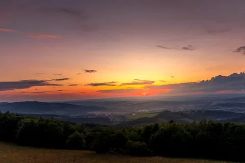 Sunset with view on landscape with fully colored clouds orange and purple and Stock-Fotos