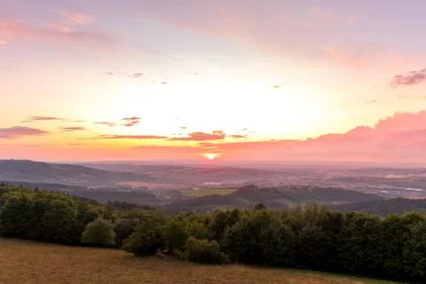 Sunset with view on landscape with fully colored clouds and orange sun goes d Фото