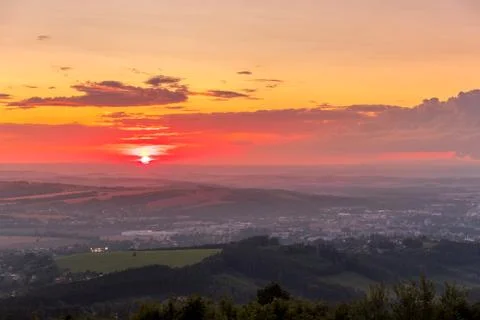 Sunset with view on landscape with fully colored clouds and orange sun goes d Stock-Fotos