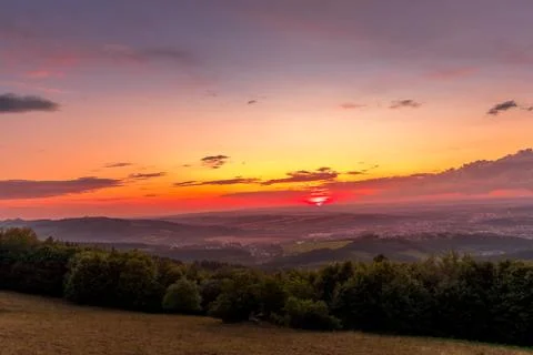 Sunset with view on landscape with fully colored clouds and orange sun goes d Stock-Fotos