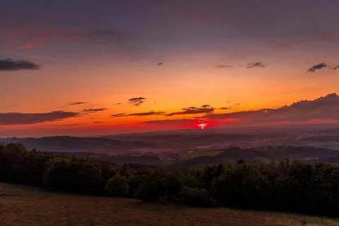 Sunset with view on landscape with fully colored clouds and orange sun goes d Stockfoto's