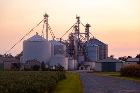 A sunset view of the large industrial size farm with large silos and granaries Stock Photos