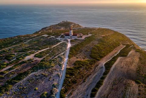 Sunset view of lighthouse, cliffs and sea horizon, cape Espichel, Portugal Stock Photos