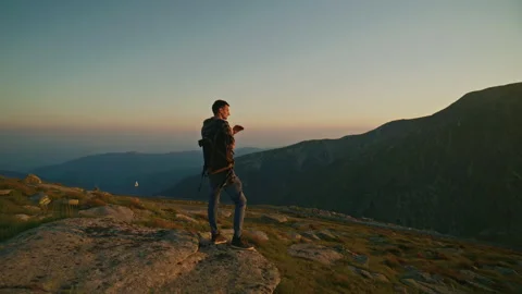 Sunset view from a mountain with a person standing on rocky ground enjoying the Stock Footage 345634569