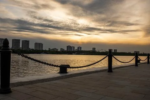 Sunset View Over the Calm River With City Skyline and Chain Barrier Along t.. Stock Photos