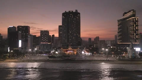 Sunset view over coastal city with tall buildings lively waterfront promenade Stock Footage 297928802
