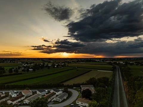 Sunset View Over Fields and Homes With Railroad Tracks Under a Cloudy Sky Stock Photos