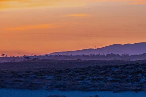 Sunset view over hills with wind turbines and distant lights Stock Photos