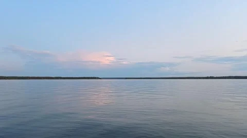 Sunset view over the lake with reflections and light clouds in the sky during ev Vídeo Stock 329433166