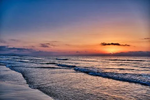 Sunset view over the ocean with waves crashing on the shore during twilight.. Stock Photos