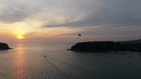 Sunset view of parasailing activity over calm ocean waters near island Stock Footage 336926610