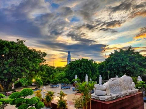 Sunset view of a park with statues and a large figure in the background Stock Photos