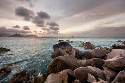 Sunset view to praslin from la digue, seychelles with granite rocks in the fo Stock Photos