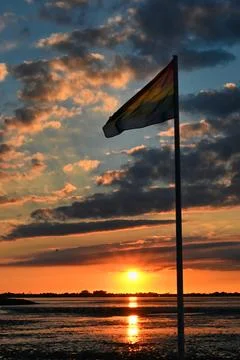 Sunset view with rainbow flag by the water Stock Photos