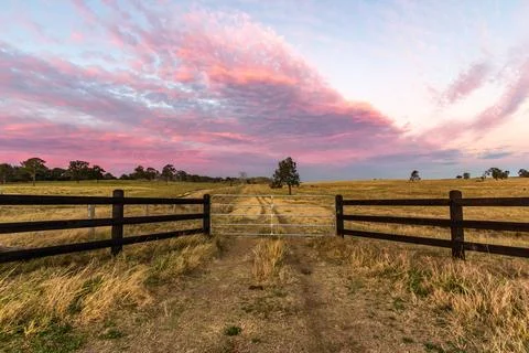 Sunset view of a rustic timber fence overlooking a rural paddock Stock Photos