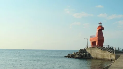 A sunset view of the sea with a red lighthouse A landmark horse-shaped lighthous Stock Footage 119509754