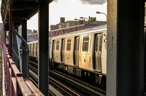 Sunset view of a subway train approaching a station on an elevated track in.. Stock Photos