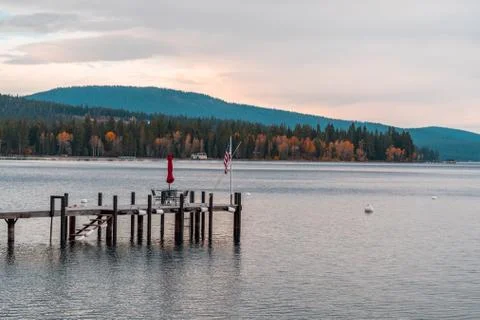Sunset view of a table, chairs and a U.S. flag on a pier on the shore of Lake Stock Photos
