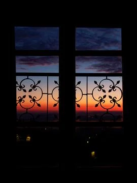 Sunset view through ornate window in Tuscany, Italy, dramatic orange and bl.. Foto stock